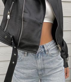 a woman wearing a black leather jacket and jeans with her hand on her hip pocket