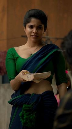 a woman in a green and blue sari holding a plate with food on it