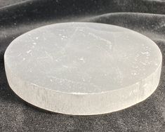 a round white object sitting on top of a black table covered in sand and water