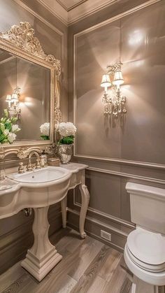 a white toilet sitting next to a sink in a bathroom under a mirror and lights