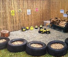 there are many tires on the ground in front of a wall with logs and other items