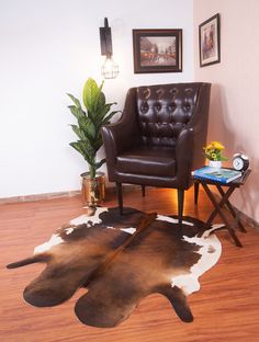 a living room with a cow hide rug on the floor and a chair next to it