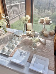 a table topped with cupcakes next to a window