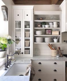 a kitchen filled with lots of white cupboards next to a sink and counter top