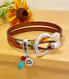 "This leather cord is beautifully finished in streaks of orange, turquoise, and beige ... much like a western sunset. The color variations are unique and organic and no two bracelets are exactly the same. Finished with a charm set of genuine turquoise with a small round of amber on top, you'll love the attention to detail. Best part: you can choose from a silver Om charm or a lotus flower! **May 12 update: currently the lotus flower is available. The aesthetic is both Boho and Western Chic and w Adjustable Orange Bohemian Wrap Bracelet, Adjustable Artsy Jewelry, Adjustable Artsy Jewelry For Everyday, Adjustable Artsy Everyday Jewelry, Everyday Bohemian Nickel Free Wrap Bracelet, Adjustable Spiritual Wrap Bracelet, Boho Leather Jewelry, Western Sunset, Turquoise Wrap Bracelet