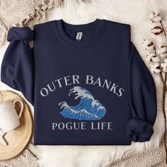 Stay warm and stylish with our Outer Banks Embroidered Pogue Life Sweatshirt, perfect for fans of the Outer Banks TV show who love the beach lifestyle. This cozy sweatshirt is designed with a classic Pogue Life logo, making it an ideal choice for those chilly beach nights and spring break getaways. With its relaxed fit and soft, comfortable fabric, this Outer Banks sweatshirt is a must-have for anyone embracing the coastal adventure spirit. * 50% cotton, 50% polyester * Pre-shrunk * Classic fit Outer Banks T Shirt, Outer Banks Tv Show, Pogue Life Outer Banks, Spring Break Getaways, Beach Nights, Pogue Life, Outer Banks Beach, Beach Sweatshirt, Life Logo