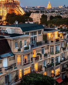 the eiffel tower is lit up at night in front of many apartment buildings