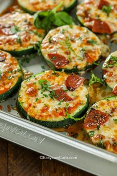 zucchini and pepperoni pizzas in a baking pan on a wooden table