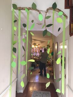 a man is walking down the hallway in front of a door decorated with green leaves