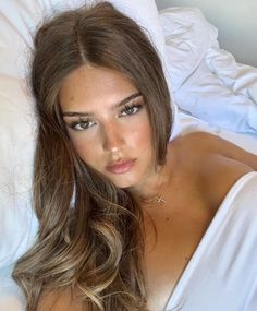 a beautiful young woman laying in bed with her eyes closed and long hair flowing over her shoulder