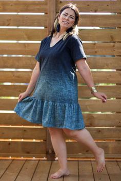 a woman in a blue dress standing on a wooden deck