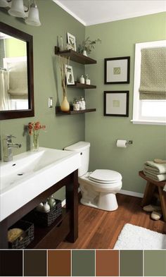 a bathroom with green walls and white fixtures, including a sink, toilet, mirror, rugs and pictures on the wall