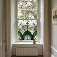 a stained glass window in the corner of a room with wood flooring and white walls