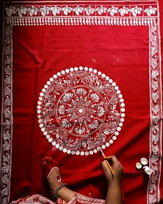 a person is drawing on a red cloth