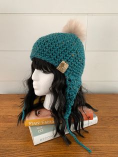 a knitted hat with a pom - pom sits on top of a book