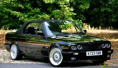 a black convertible car parked in front of some trees