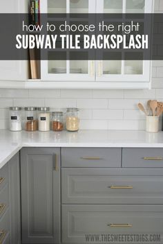 a kitchen with gray cabinets and white subway backsplash, gold pulls on the cabinet doors