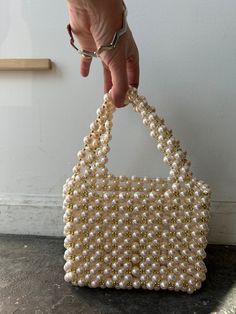 Pearl and Gold Beaded Party Bag. Every life of the part needs a statement bag, and this is just the one! The outer later is composted of large faux-pearls and small gold beads that create the handles as well. Interior is a plastic lucite rectangular compartment, the perfect size of the essentials on a night out. Bring a bit of bling to your look! In excellent condition. Approx. Measurements: Interior compartment: 7" (L) x 2.5" (W) x 6" (H) Height of bag with handles: 11" Rectangular Evening Bag With Pearl Handle, Party Rectangular Bag With Gold Beads, Rectangular Party Bag With Gold Beads, Rectangular Evening Bag With Pearl Embroidery, Elegant Rectangular Bags With Gold Beads, Elegant Rectangular Gold Beaded Bags, Gold Rectangular Bag With Pearl Material, Rectangular Gold Bag With Pearl Material, Rectangular Gold Pearl Bag