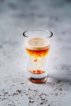 a shot glass filled with liquid sitting on top of a cement floor next to a sign that says jellyfish shot