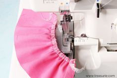 the sewing machine is working on the pink dress