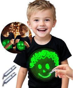 a little boy that is holding a green light up t - shirt in his hand