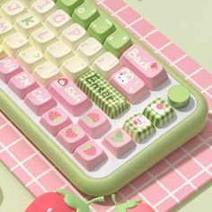 a computer keyboard sitting on top of a pink and green table next to an apple