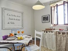 a table with two glasses of orange juice on it in front of a kitchen window