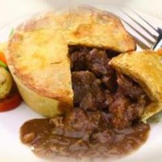 a beef pot pie on a white plate with a fork and knife next to it