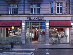 a store front with red awnings on the windows and an empty street in front