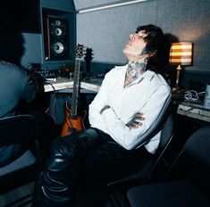 a man with tattoos is sitting in front of a guitar and recording equipment, while looking up into the sky