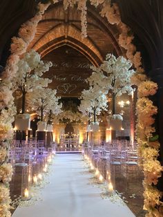 the aisle is decorated with white flowers and candles