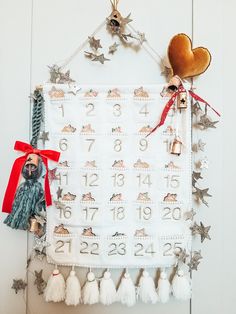 a christmas calendar hanging on the wall with ornaments around it and a santa clause ornament