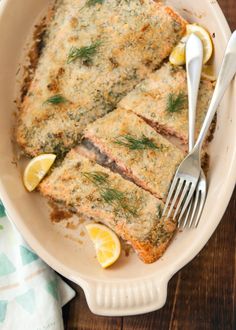 two slices of fish in a dish with lemons and dill