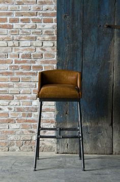 a brown chair sitting in front of a brick wall next to a blue wooden door