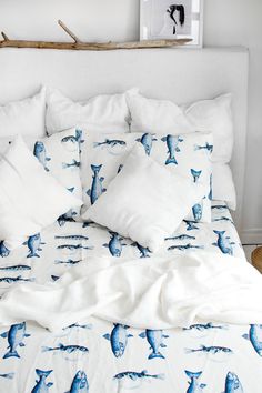 a bed with white sheets and blue fish print on the comforter, along with two pillows