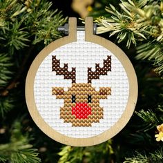 a cross stitch christmas ornament hanging from a tree