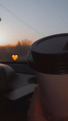 a person holding a coffee cup in their hand with a heart - shaped object behind them