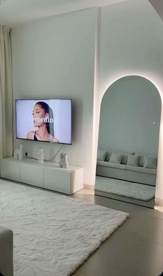 a flat screen tv mounted to the side of a wall next to a white couch