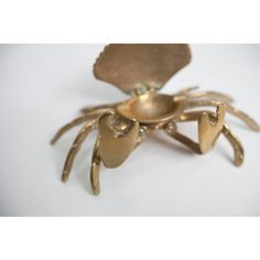 a gold plated crab shaped object on a white surface