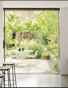 an open glass door leading into a garden