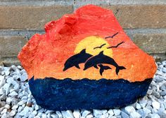 a rock with two dolphins painted on it