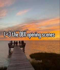 people are sitting on benches at the end of a pier that leads to an ocean