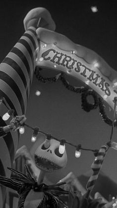 a black and white photo of a christmas sign with skeletons hanging from it's sides