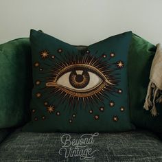 a green couch with a decorative pillow on it and an eye drawn in the middle