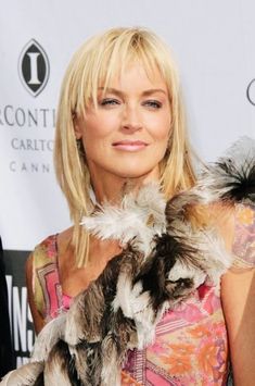 a woman with blonde hair holding a cat in her arms and posing for the camera