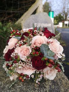 a bridal bouquet sitting on top of a rock next to a headstone in the background