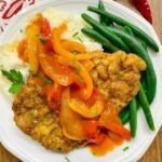 a white plate topped with meat and veggies on top of mashed potatoes