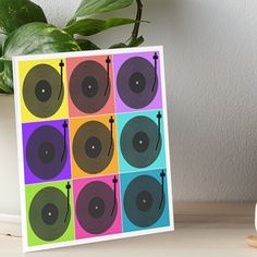 an art board with different colored records on it and a potted plant in the background