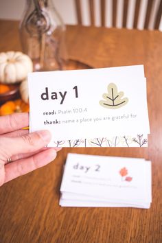 a person holding up a card with the words day 1 written on it next to some pumpkins