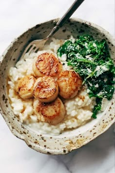 a bowl filled with rice, broccoli and scallops on top of it